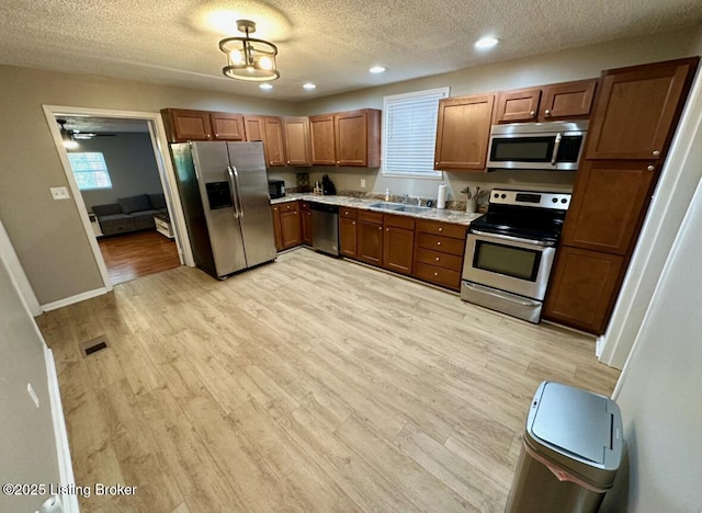 2512 S 4th St, Louisville, KY 40208 - kitchen with appliances with stainless steel finishes, a textured ceiling, light countertops, light wood-type flooring, and brown cabinets