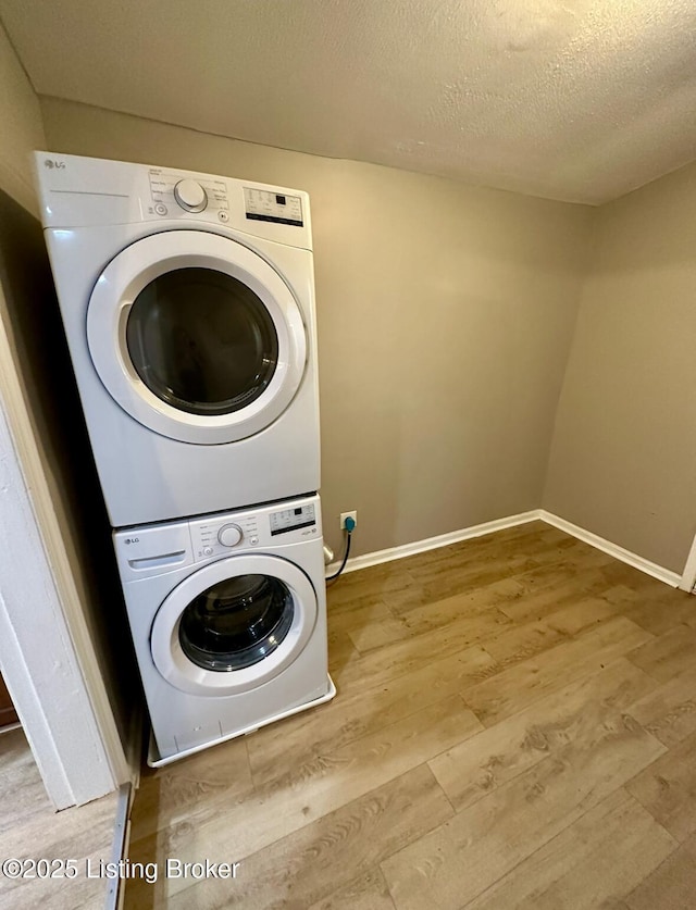 2512 S 4th St, Louisville, KY 40208 - laundry area featuring stacked washing machine and dryer, wood finished floors, baseboards, and a textured ceiling