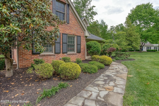 view of side of home with brick siding and a yard