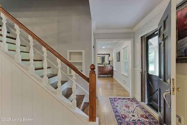 foyer entrance with wood finished floors, stairs, and crown molding