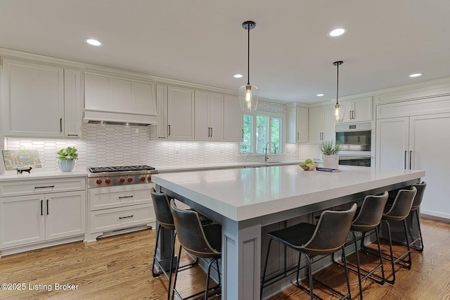 kitchen with light wood-style flooring, a kitchen bar, light countertops, white cabinets, and tasteful backsplash