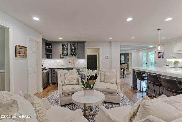 living area featuring recessed lighting, light wood-style flooring, and bar with sink