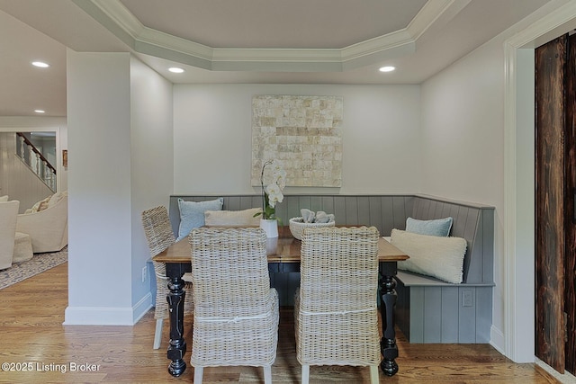 dining room featuring crown molding, breakfast area, a raised ceiling, wood finished floors, and stairway