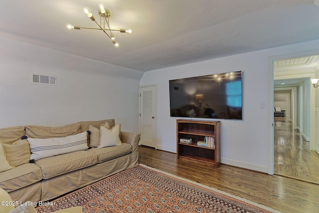 living room featuring wood finished floors, a chandelier, baseboards, and vaulted ceiling