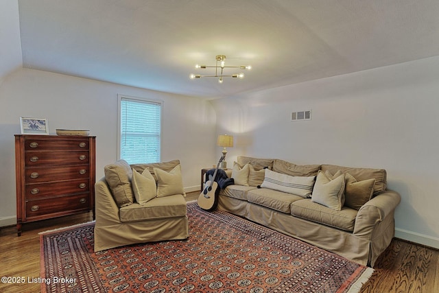 living area featuring wood finished floors, a chandelier, baseboards, and vaulted ceiling