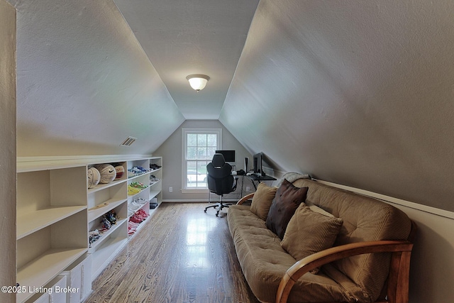 sitting room featuring wood finished floors, a textured ceiling, vaulted ceiling, and baseboards