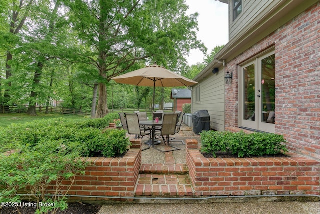 view of patio with french doors, fence, outdoor dining space, and grilling area
