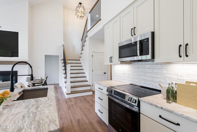 4227 Stilger Cir, Louisville, KY 40299 - kitchen featuring appliances with stainless steel finishes, light wood-type flooring, backsplash, light stone counters, and white cabinets