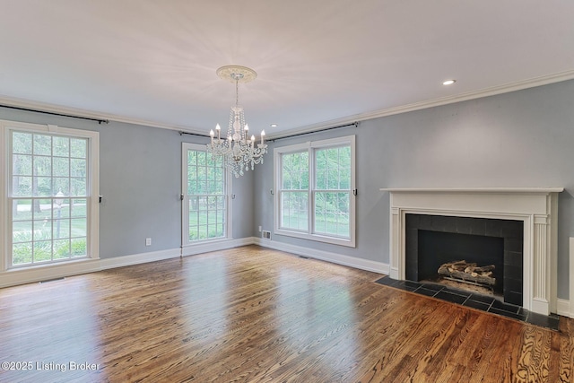 unfurnished living room featuring crown molding, plenty of natural light, wood finished floors, a chandelier, and baseboards