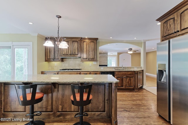 kitchen with appliances with stainless steel finishes, dark wood-style flooring, a sink, decorative backsplash, and light stone counters