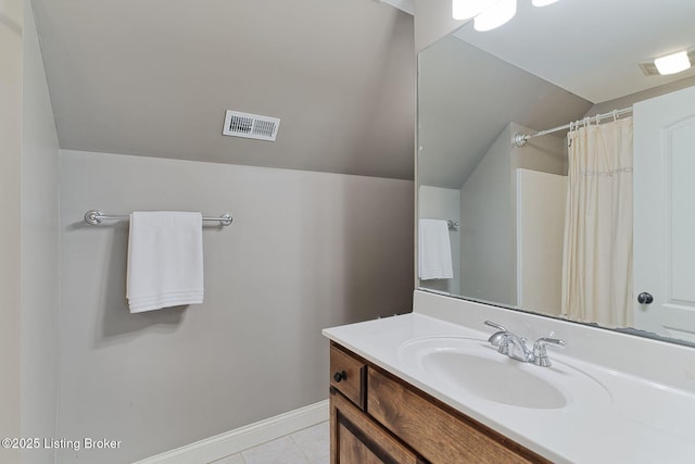 bathroom featuring lofted ceiling, vanity, baseboards, and tile patterned floors
