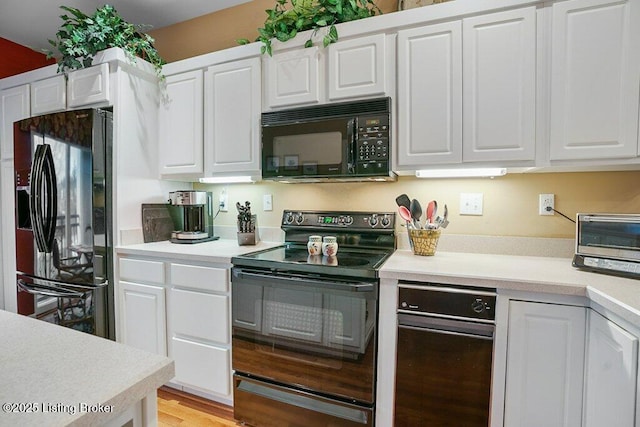 kitchen with black appliances, light countertops, white cabinetry, and light wood-style floors