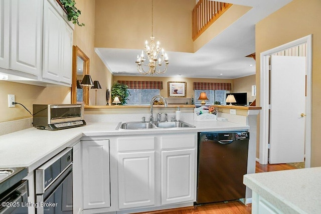 kitchen with dishwasher, a sink, white cabinetry, a chandelier, and a high ceiling