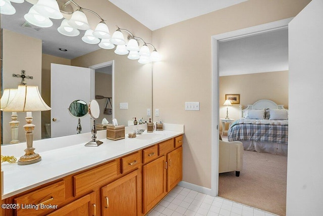 ensuite bathroom with tile patterned flooring, vanity, and baseboards