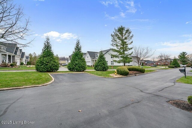 view of asphalt road with a residential view and curbs
