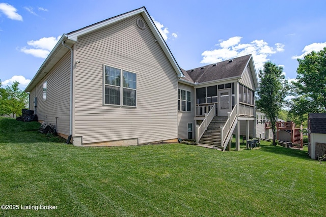 back of property featuring a sunroom, stairway, and a lawn