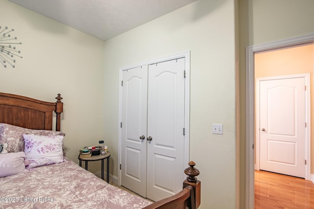 bedroom with a closet, light wood-style floors, and baseboards