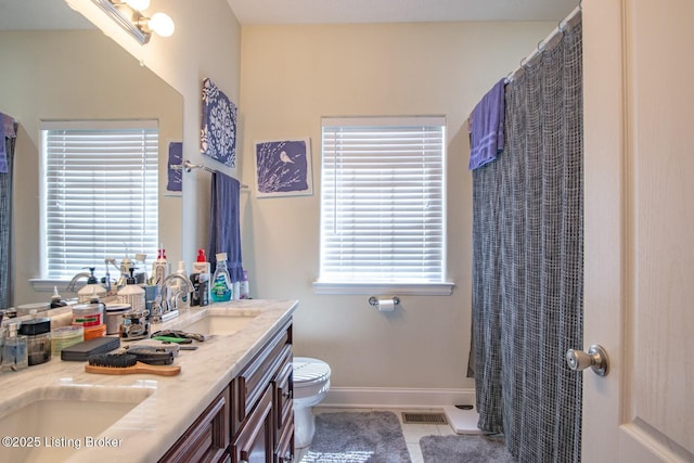 full bathroom with toilet, plenty of natural light, double vanity, and tile patterned flooring