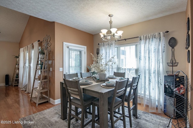 dining area featuring a chandelier, plenty of natural light, light wood-type flooring, baseboards, and a textured ceiling