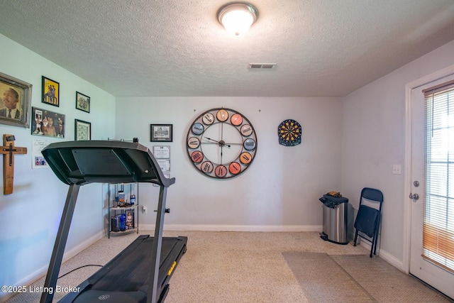 workout area featuring a textured ceiling, carpet, and baseboards