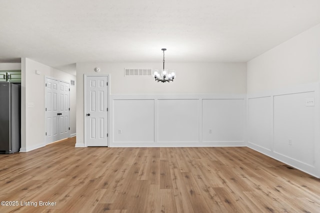 510 University Dr, Radcliff, KY 40160 - unfurnished dining area featuring a decorative wall, a chandelier, light wood finished floors, and a wainscoted wall