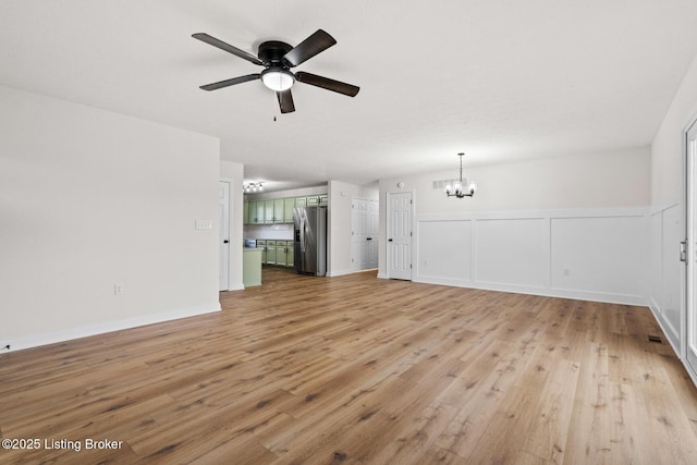 510 University Dr, Radcliff, KY 40160 - unfurnished living room with a chandelier, light wood-style flooring, a ceiling fan, and a wainscoted wall