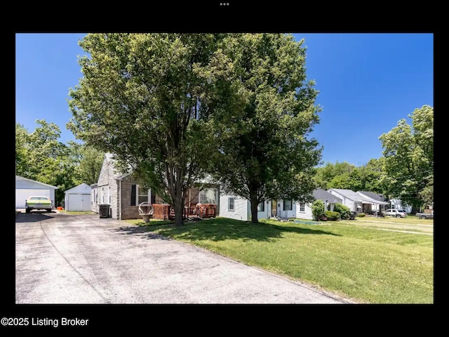 4328 S 1st St, Louisville, KY 40214 - view of property hidden behind natural elements featuring a front lawn, a detached garage, an outdoor structure, and a residential view
