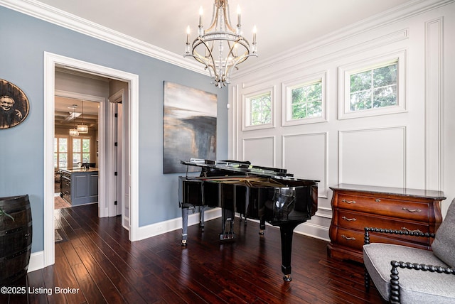 sitting room featuring baseboards, a chandelier, wood finished floors, and crown molding