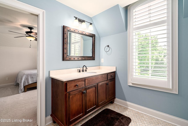 ensuite bathroom featuring lofted ceiling, a ceiling fan, baseboards, and vanity