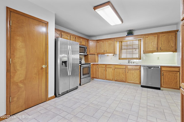 7601 Greenfield Ave, Louisville, KY 40214 - kitchen with appliances with stainless steel finishes, a sink, light countertops, backsplash, and brown cabinets
