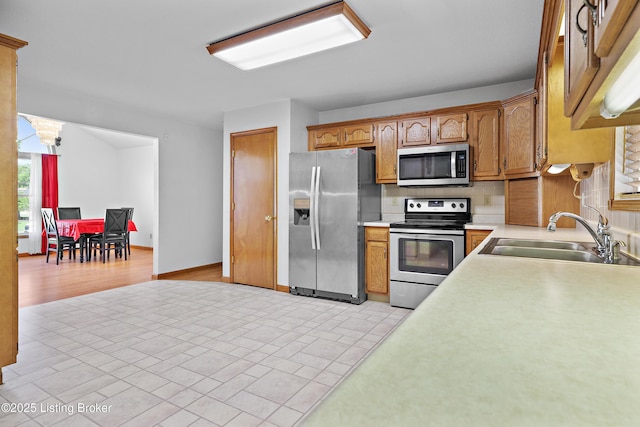 7601 Greenfield Ave, Louisville, KY 40214 - kitchen with appliances with stainless steel finishes, a sink, light countertops, decorative backsplash, and brown cabinets