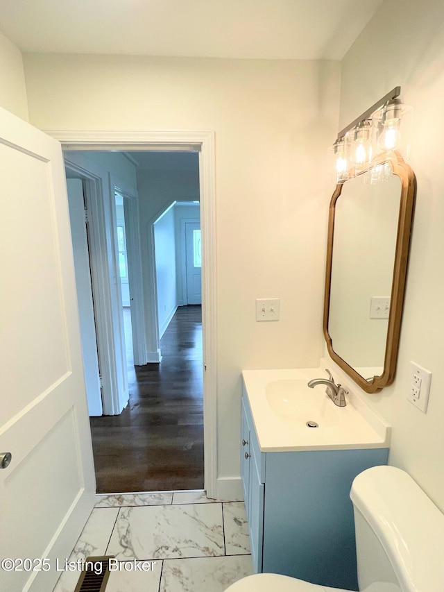 3004 Wayne Rd, Louisville, KY 40216 - bathroom featuring toilet, vanity, marble look tiles, and baseboards