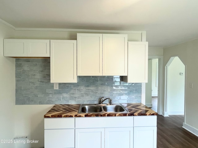 3004 Wayne Rd, Louisville, KY 40216 - kitchen featuring a sink, white cabinetry, decorative backsplash, dark wood finished floors, and arched walkways