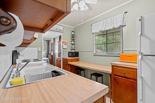 200 Derby Ave, Louisville, KY 40218 - kitchen featuring freestanding refrigerator, crown molding, tasteful backsplash, ceiling fan, and brown cabinets
