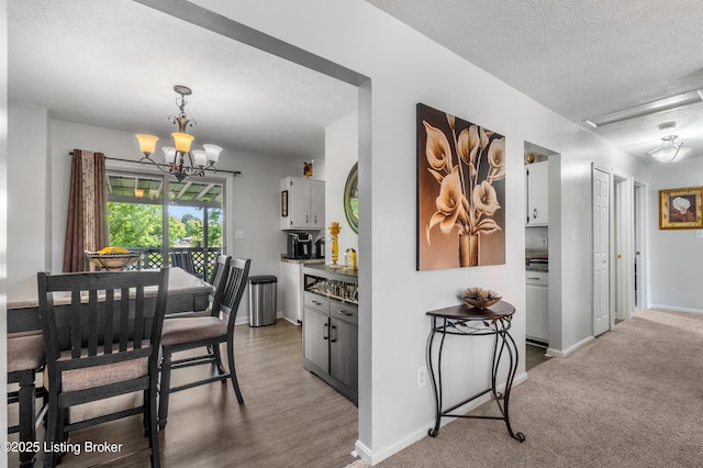 dining room with a textured ceiling, a chandelier, baseboards, and light wood-type flooring