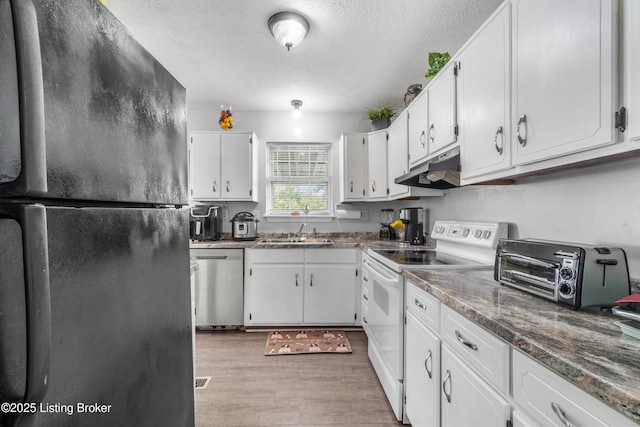 kitchen featuring electric stove, freestanding refrigerator, dishwasher, under cabinet range hood, and a sink