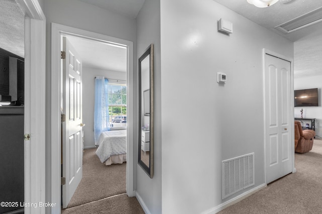 corridor with carpet floors, baseboards, and a textured ceiling