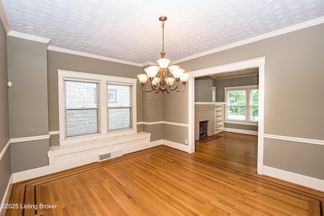 919 Eastern Pkwy, Louisville, KY 40217 - unfurnished dining area featuring a chandelier, hardwood / wood-style flooring, baseboards, and a brick fireplace