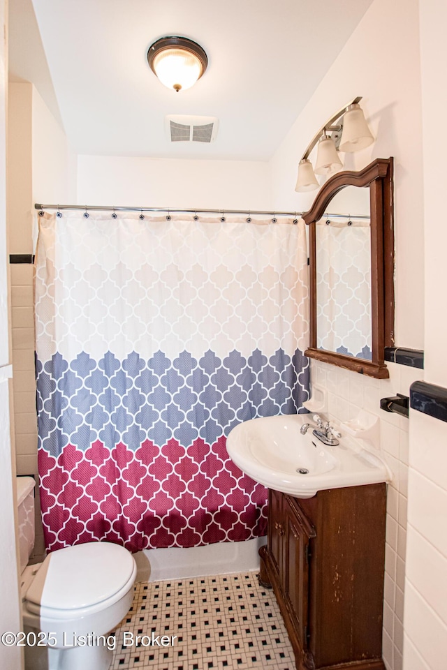 919 Eastern Pkwy, Louisville, KY 40217 - bathroom with a shower with curtain, vanity, toilet, and tile walls