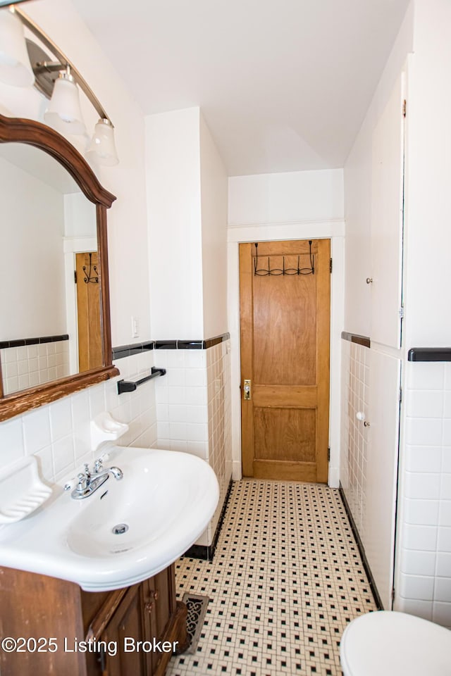 919 Eastern Pkwy, Louisville, KY 40217 - bathroom featuring tile walls, wainscoting, toilet, vanity, and tile patterned flooring