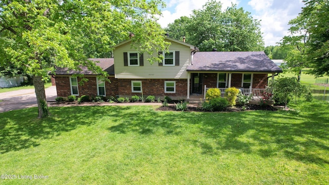 tri-level home featuring covered porch, brick siding, and a front yard
