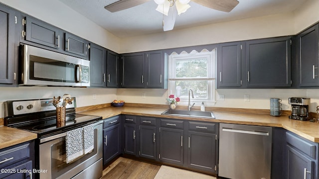 kitchen featuring appliances with stainless steel finishes, a sink, ceiling fan, and light countertops