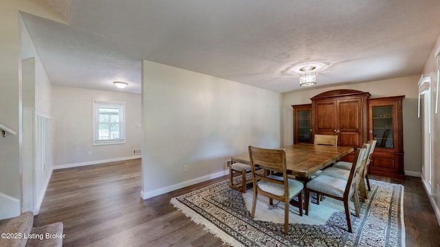 dining room featuring dark wood-style floors, baseboards, and a textured ceiling