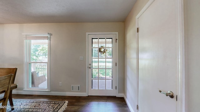 doorway featuring plenty of natural light, dark wood-style flooring, and baseboards
