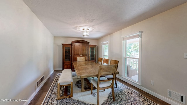dining area with dark wood-type flooring, baseboards, and a textured ceiling