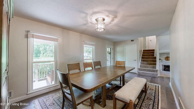 dining room featuring a textured ceiling, wood finished floors, baseboards, and stairway