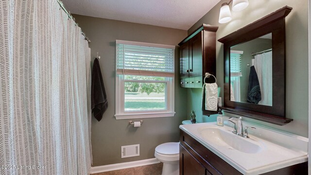 full bath with toilet, vanity, a textured ceiling, baseboards, and tile patterned flooring