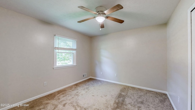 carpeted spare room with ceiling fan and baseboards
