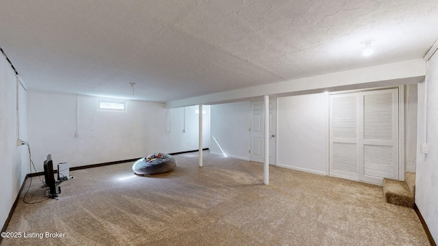 below grade area with a textured ceiling, carpet, and baseboards