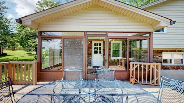 wooden deck featuring a sunroom and outdoor dining space